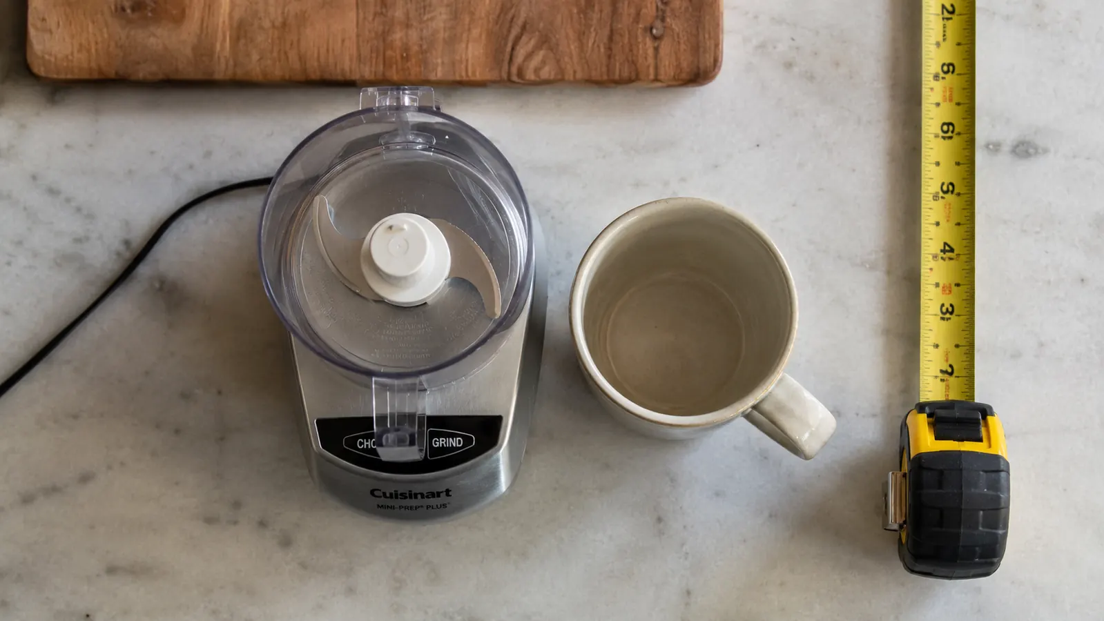 Counter space comparison showing the Cuisinart Mini-Prep Plus footprint next to a standard coffee mug, demonstrating its compact size